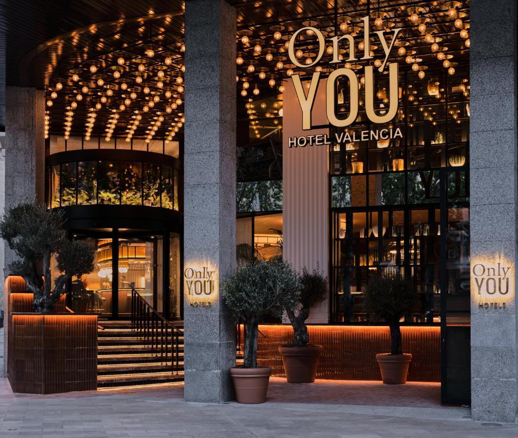 Only You Hotel Valencia Exterior photo The photo shows the entrance of a hotel named "Only YOU Hotel Valencia." The facade is modern and stylish, featuring a large, well-lit sign with the hotel name prominently displayed. The entrance is adorned with decorative lighting overhead, creating